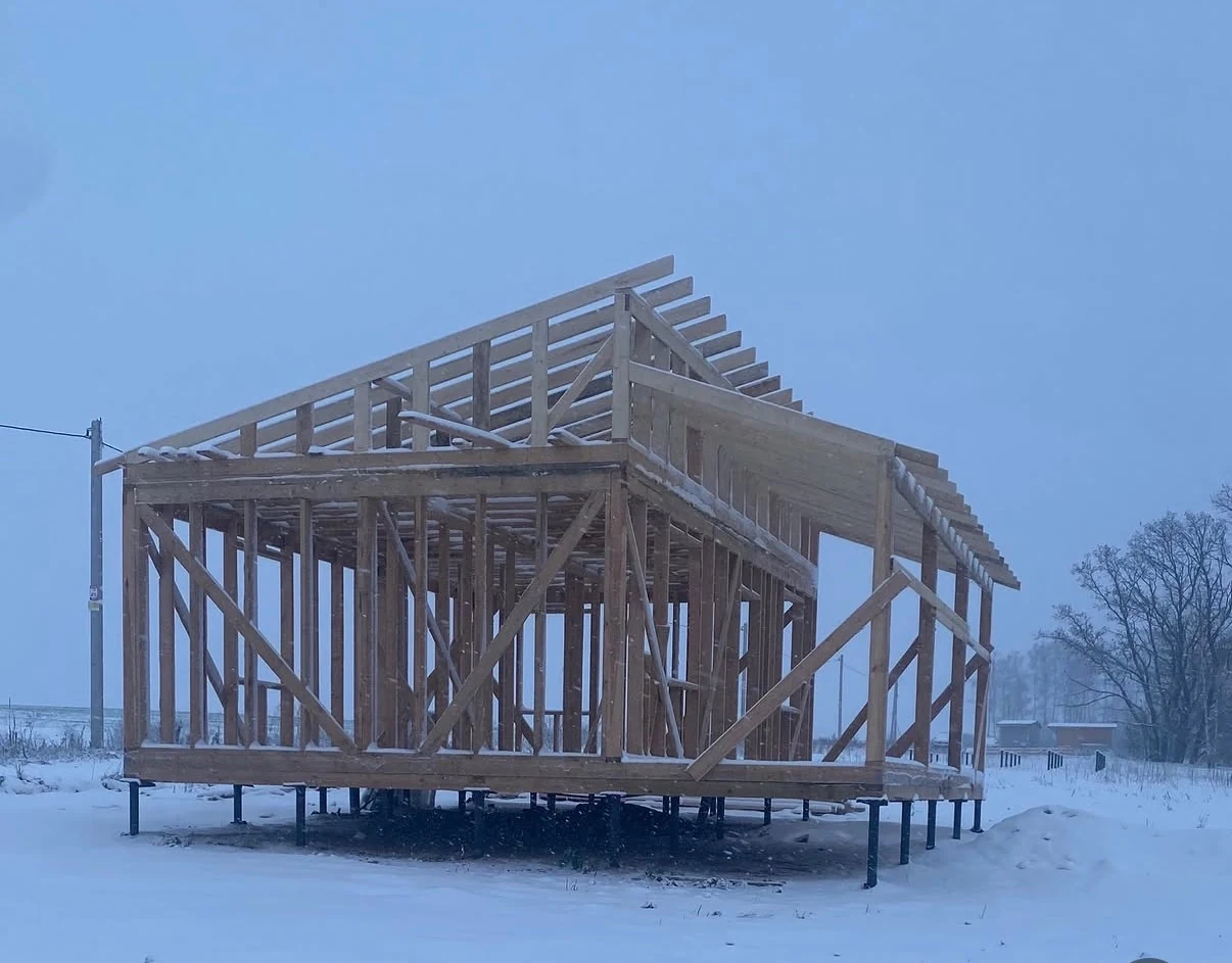 Timber-frame house structure standing on screw piles in winter