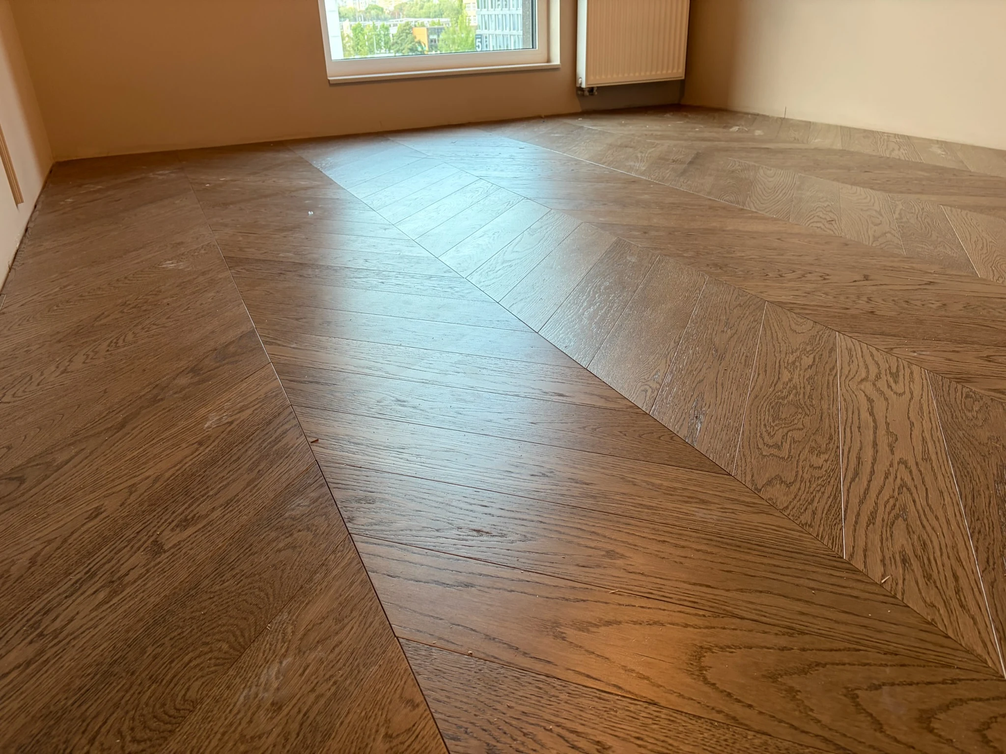 Oak parquet in French herringbone in the living room, window light running along the boards